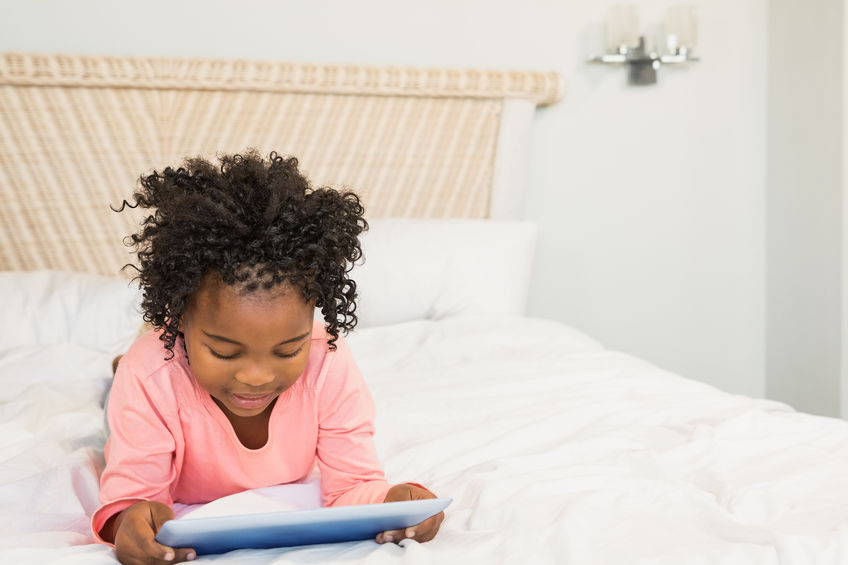 48149968 - young girl using tablet on bed at home “Put down the iPad and go play outside” say parents to tech-obsessed kids