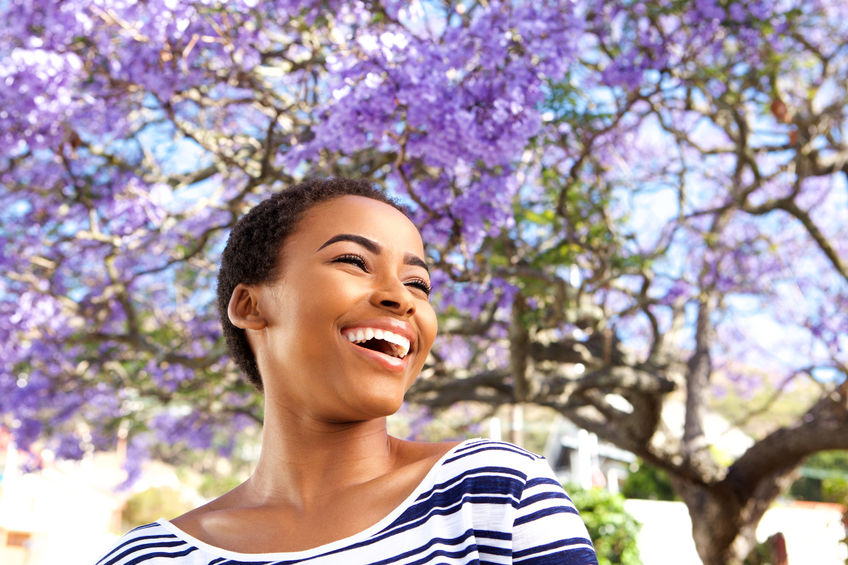 Refresh your life with a good spring clean 71517809 - portrait of attractive young black woman laughing outdoors by flower tree